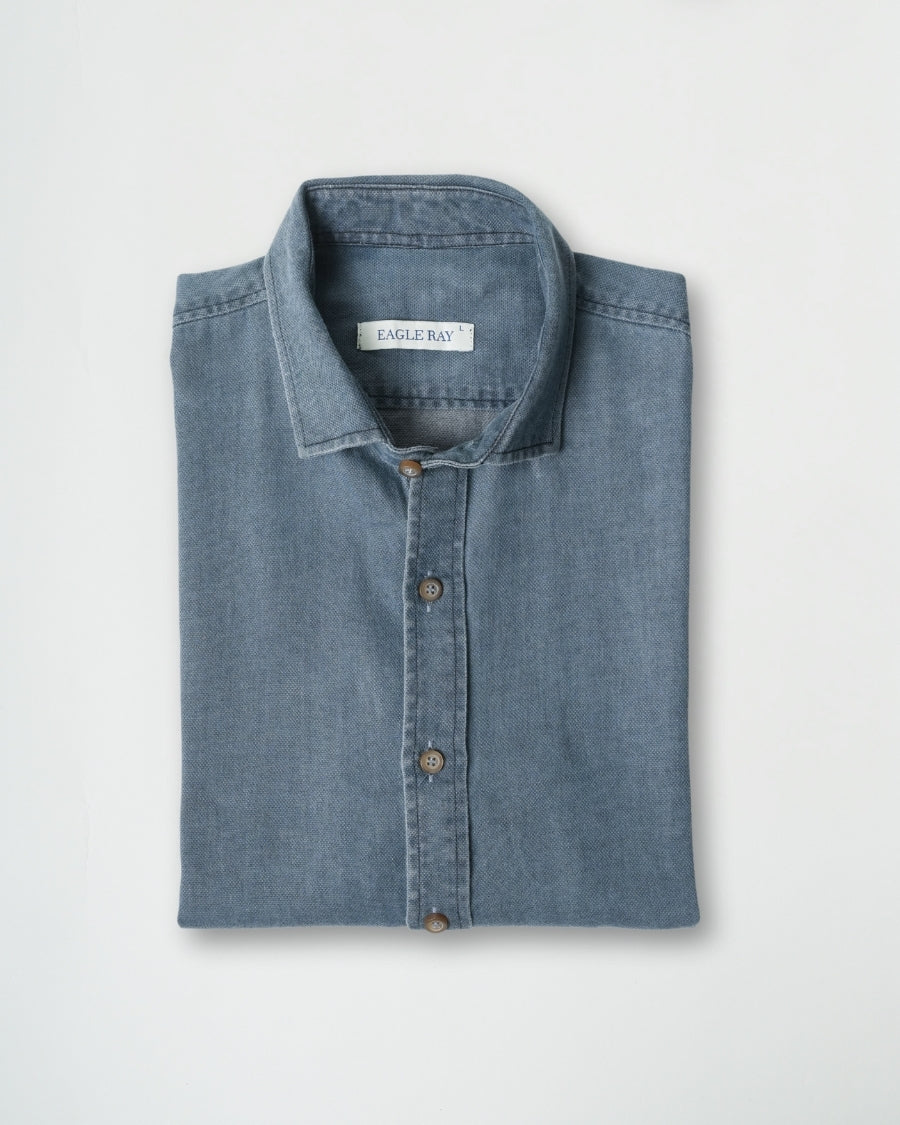 Folded blue denim shirt with 'Eagle Bay' label on a light gray background