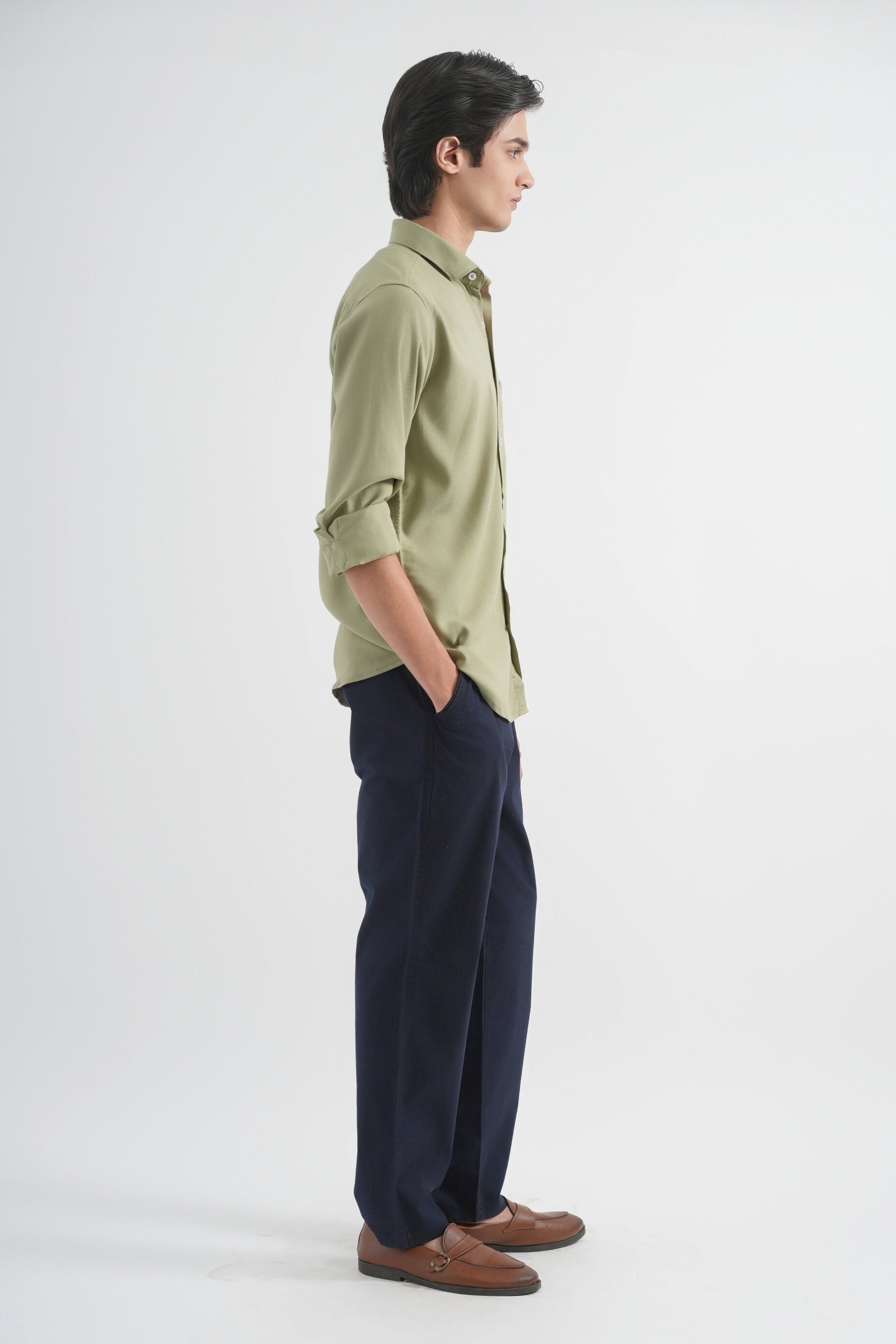 Person wearing a green shirt and dark pants on a white background