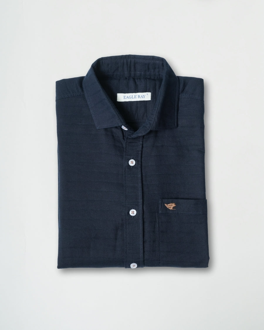 Folded navy shirt with a brand label on a light gray background