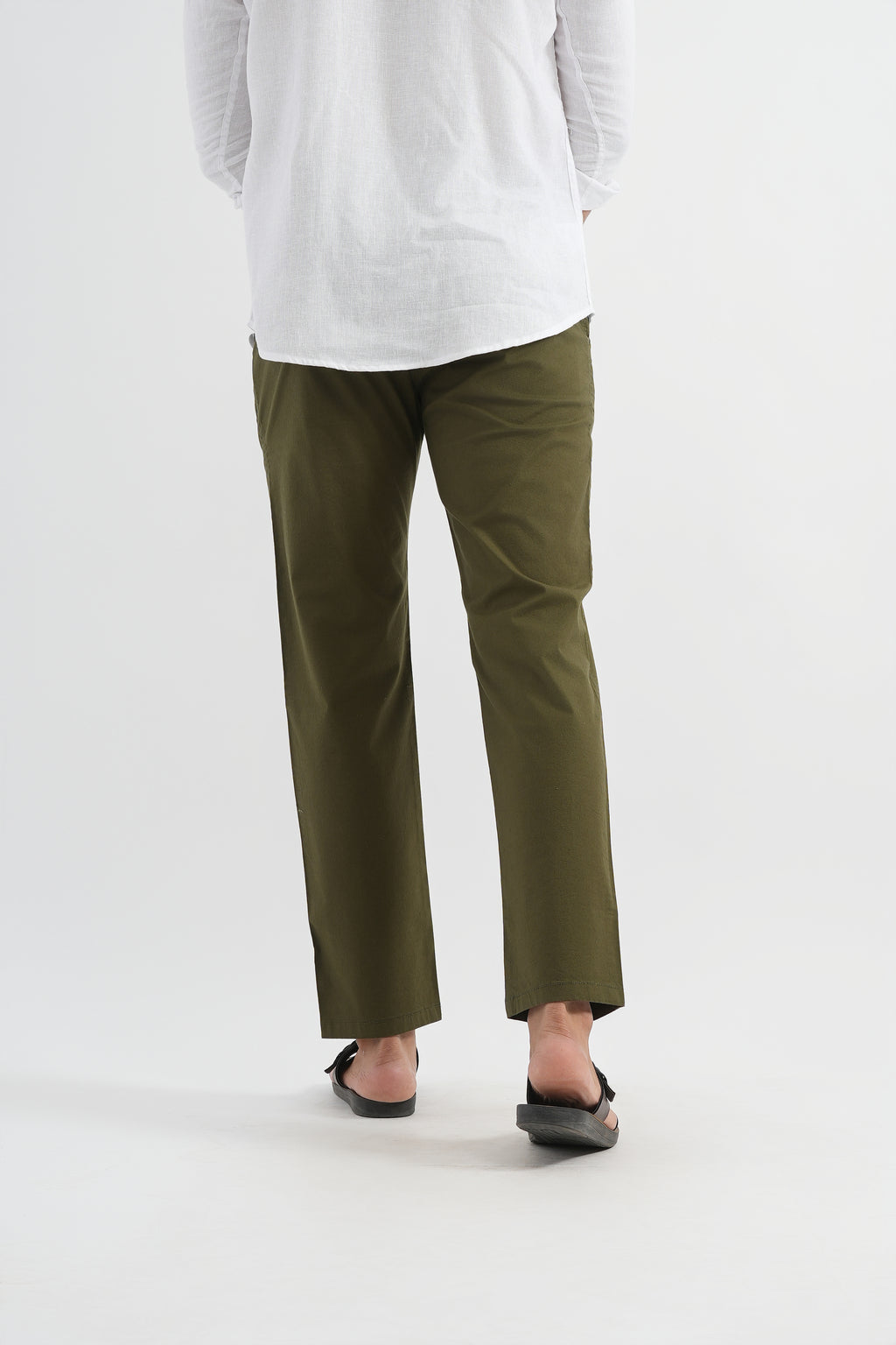 Person wearing olive green pants and a white top on a light gray background