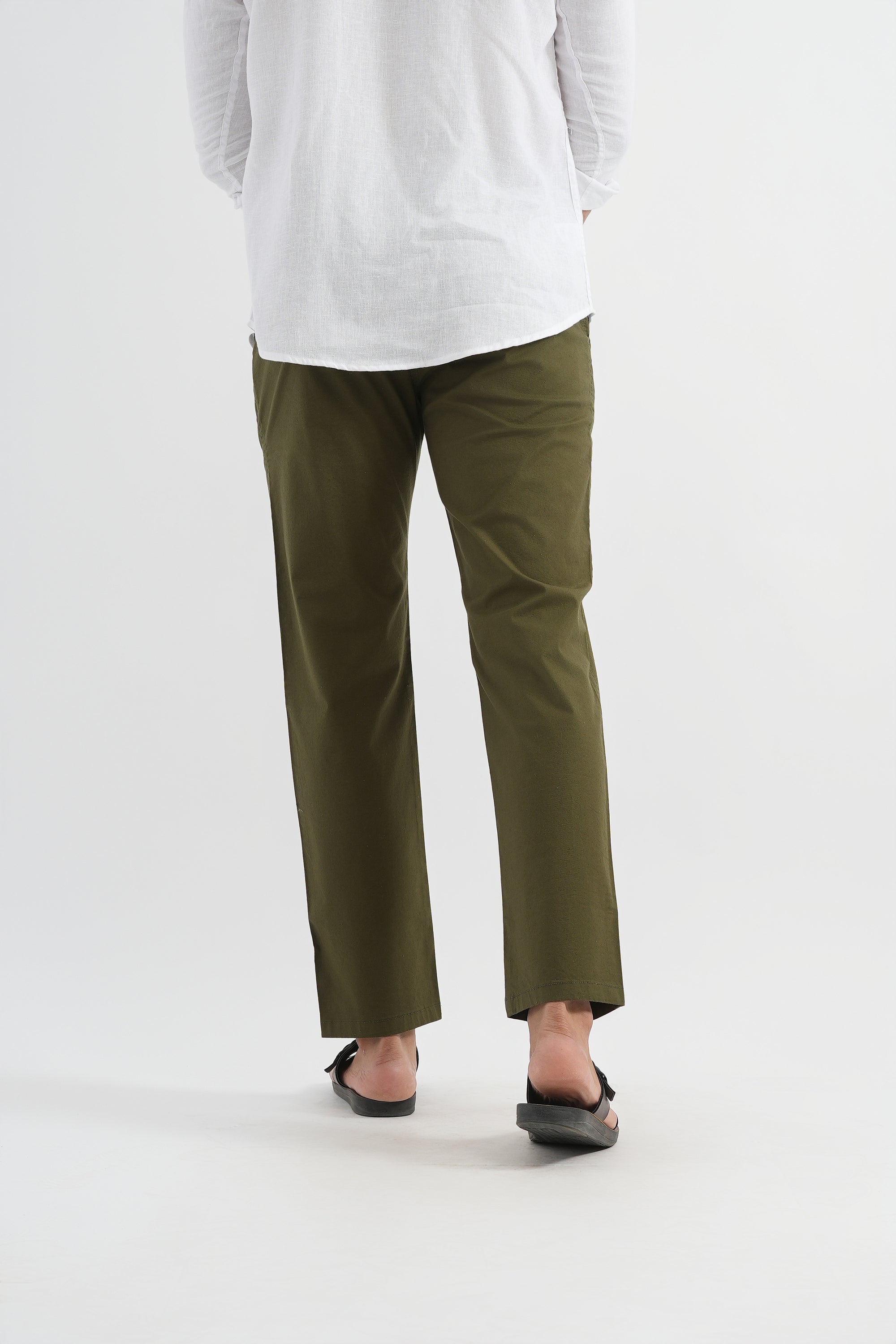 Person wearing olive green pants and a white top on a light gray background