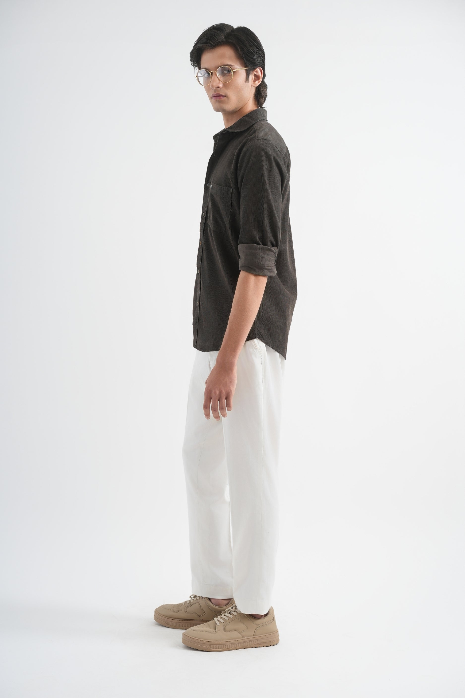 Person wearing a dark shirt and white pants on a plain background