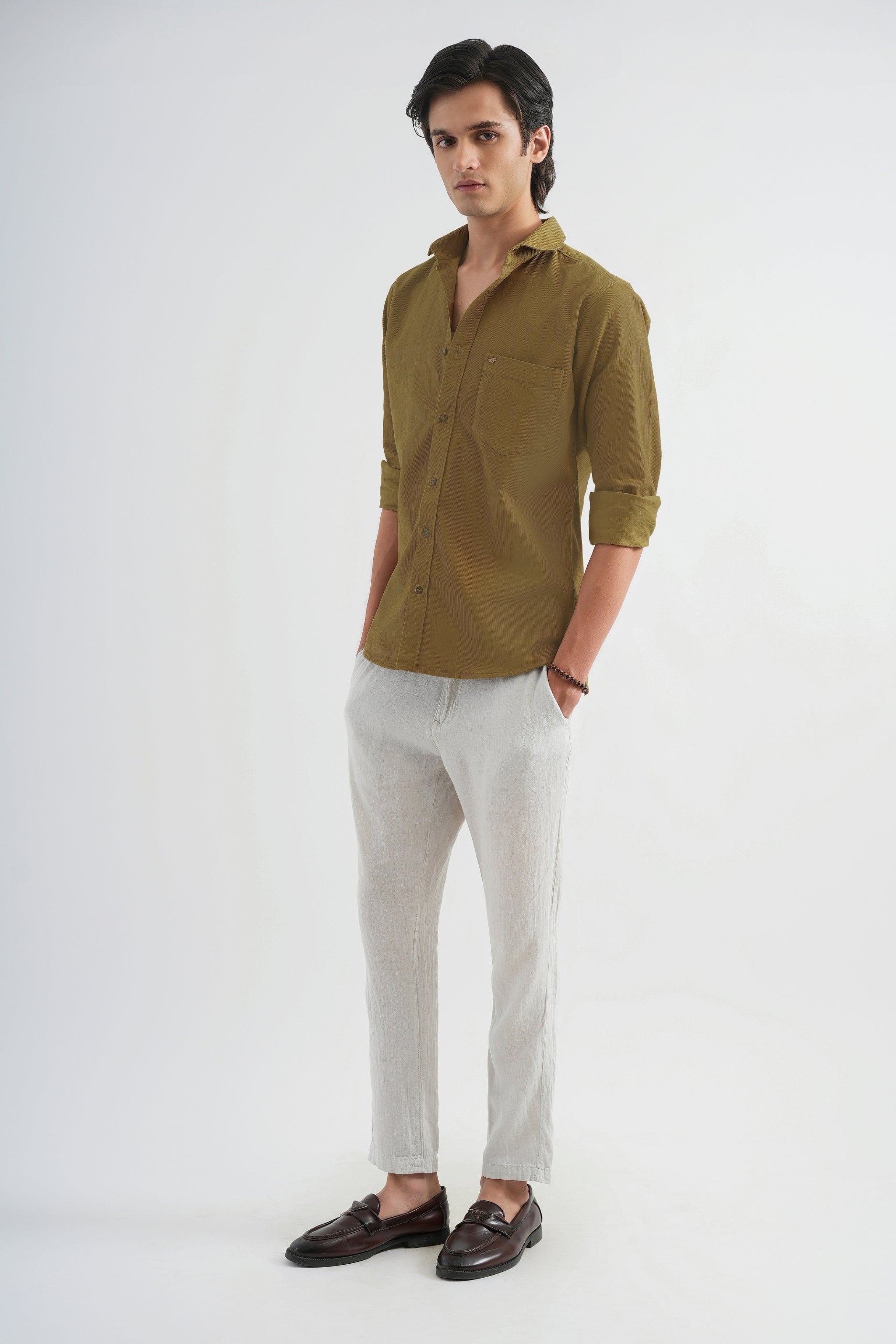 Man wearing a green shirt and light-colored pants on a white background