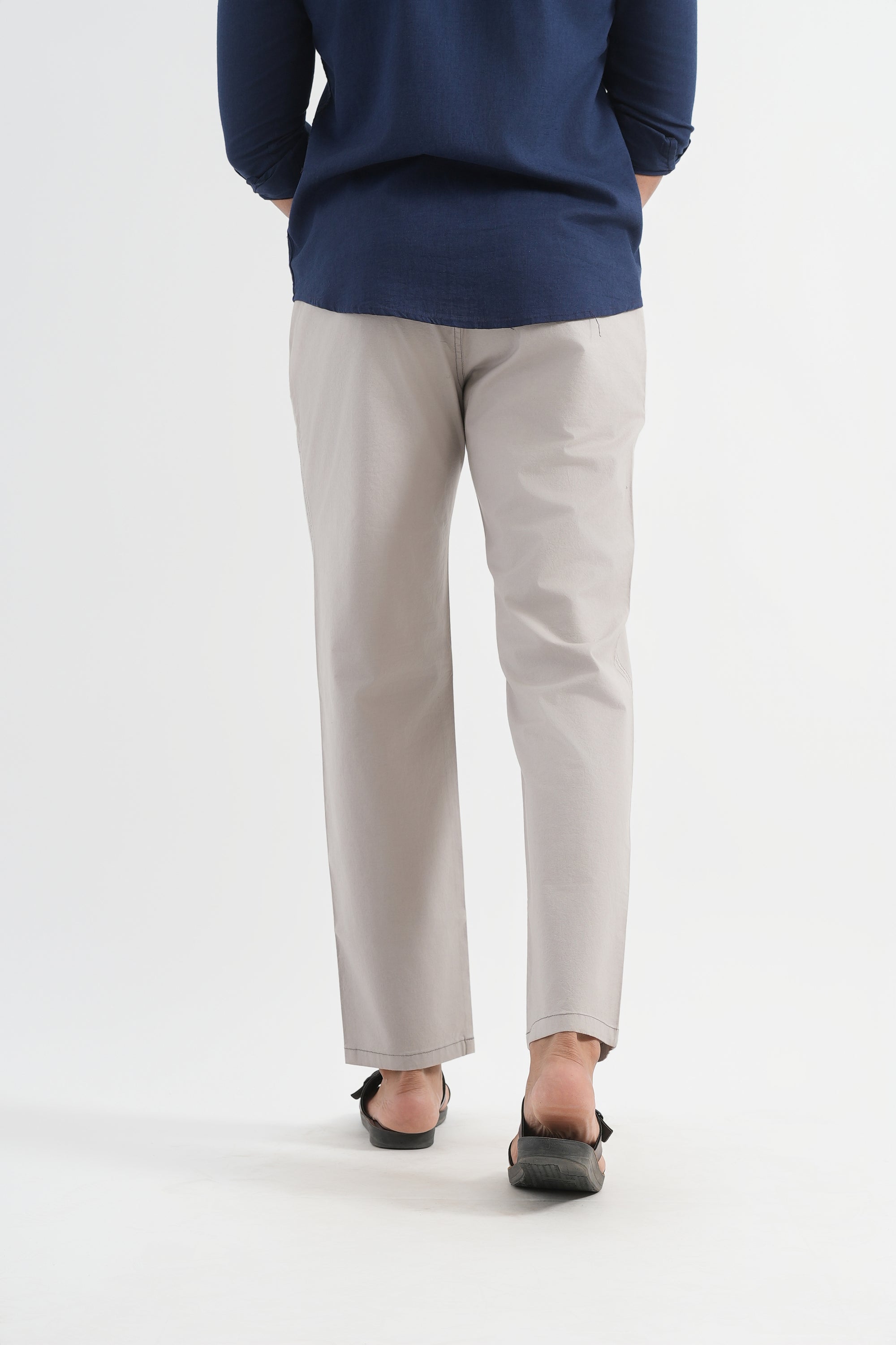 Person wearing a navy top and light gray pants on a white background