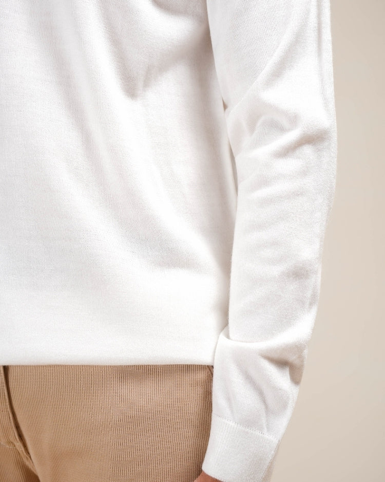 Close-up of a white long-sleeve shirt with beige pants on a neutral background