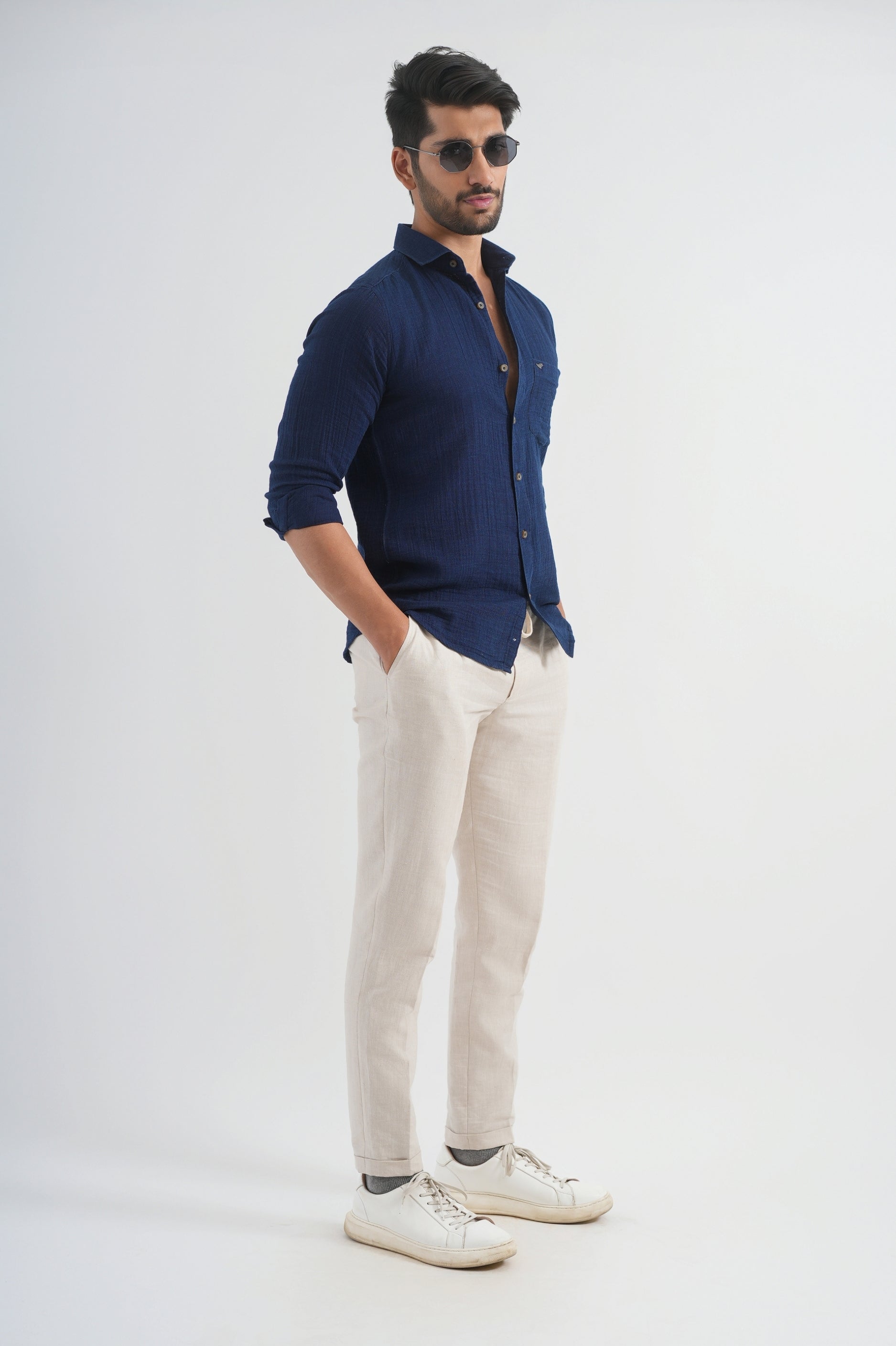 Man wearing a navy shirt and beige pants on a white background