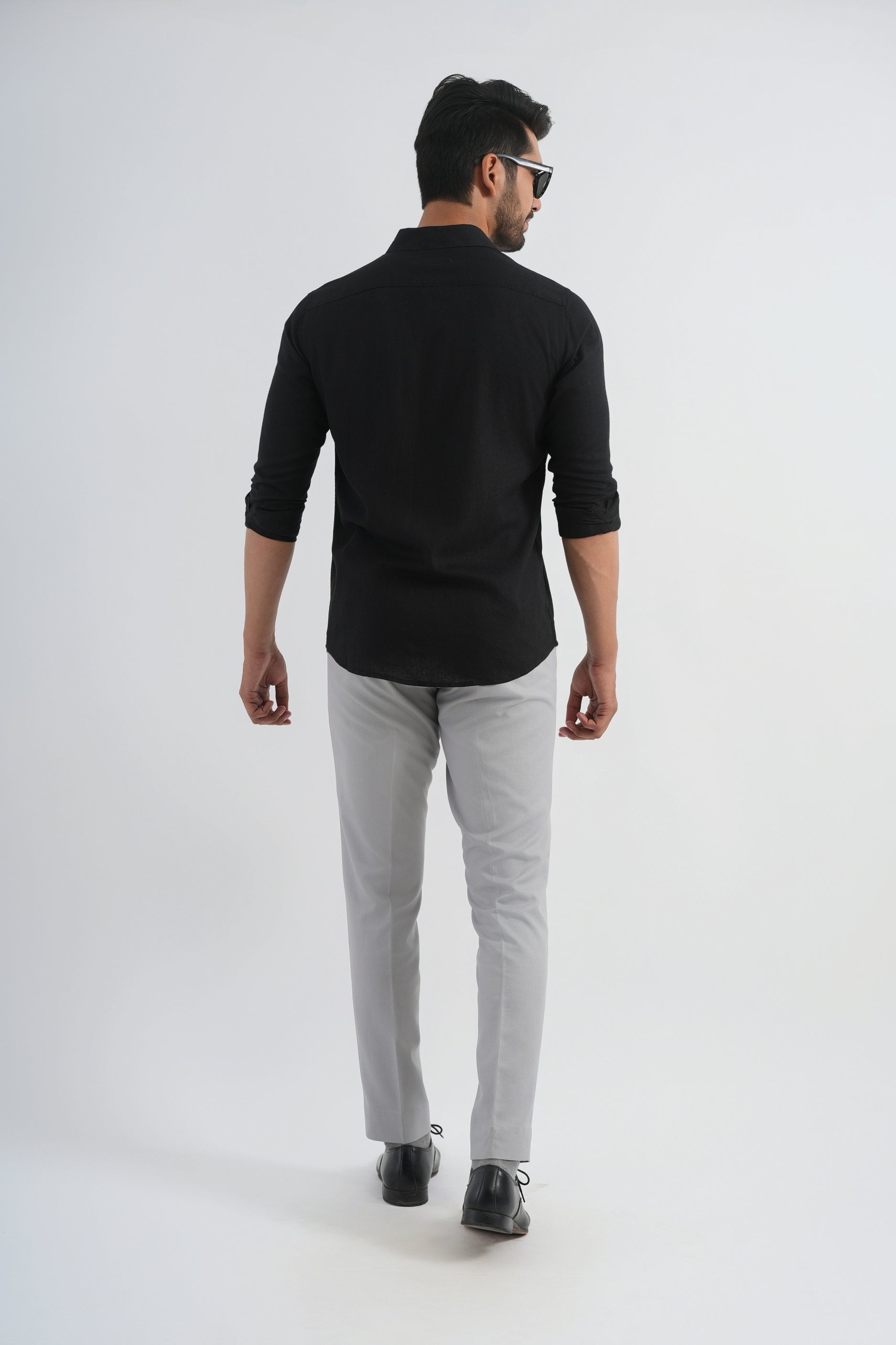 Man wearing a black shirt and gray pants on a white background