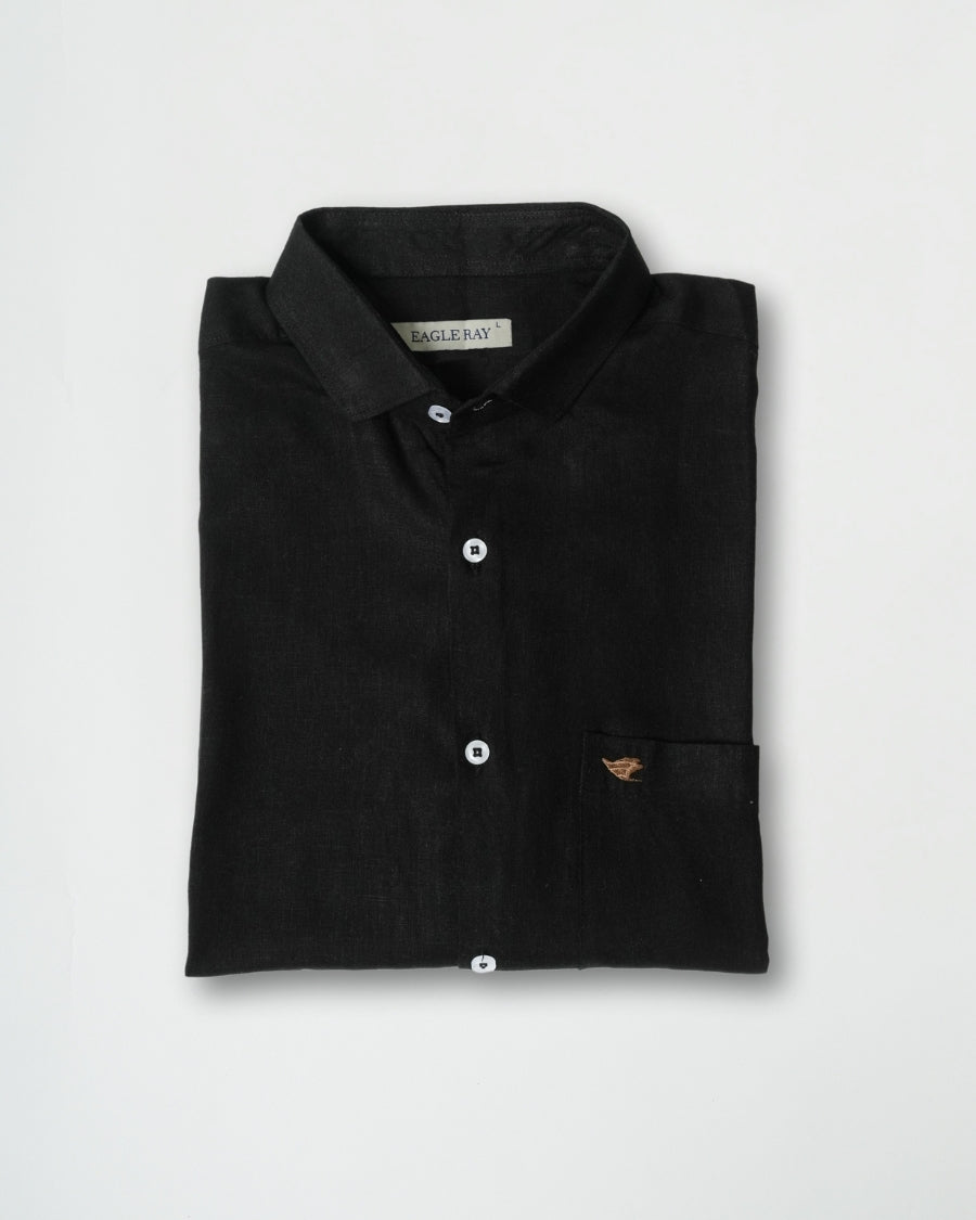 Folded black polo shirt with a brand label on a light gray background