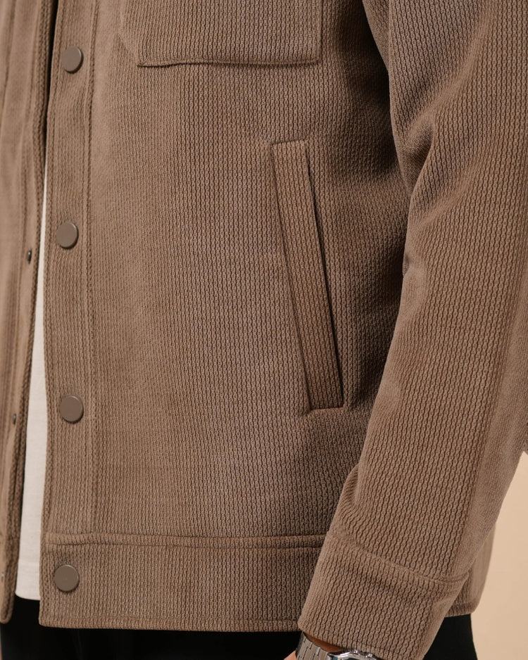 Man wearing a brown jacket against a beige background