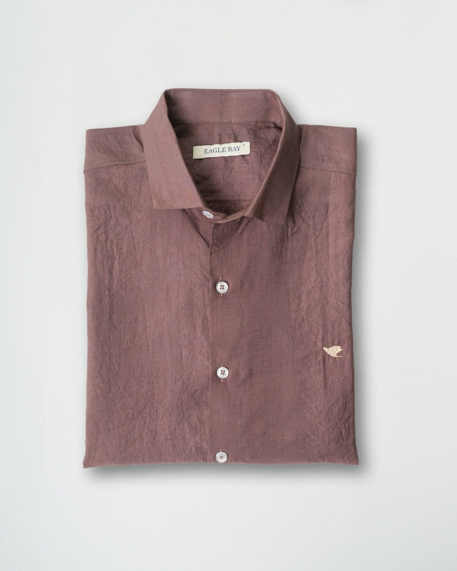 Folded brown shirt with a visible brand label on a light gray background
