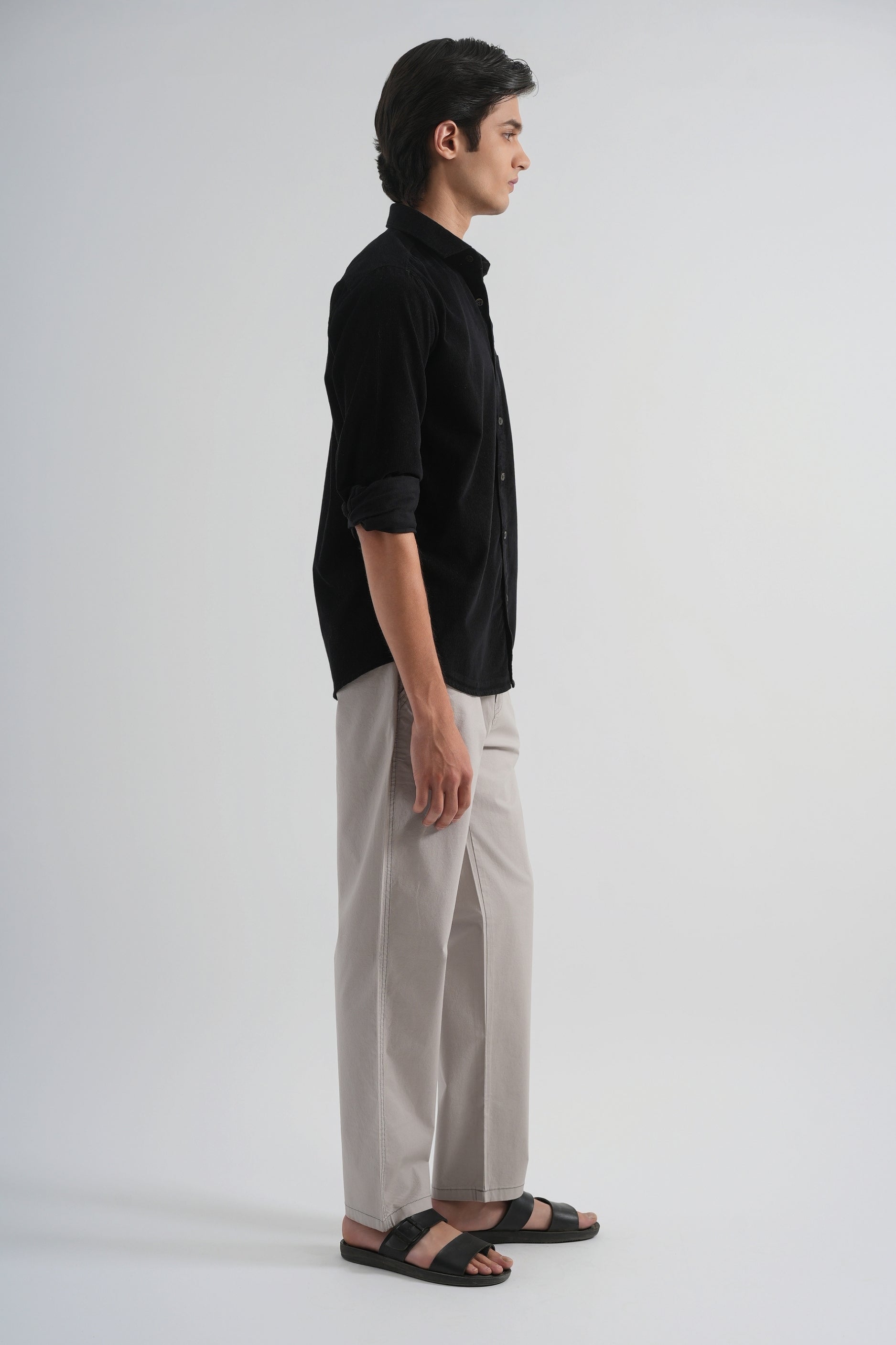 Person wearing a black shirt and gray pants on a white background