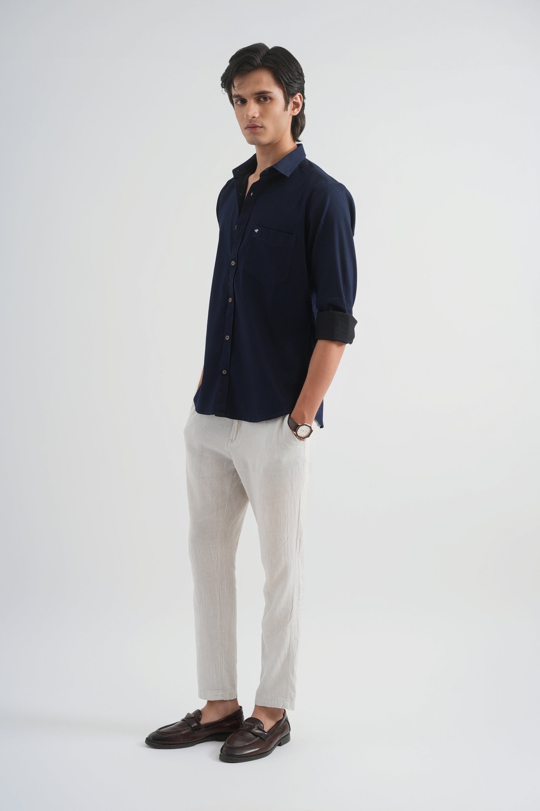 Man wearing a navy shirt and white pants on a white background