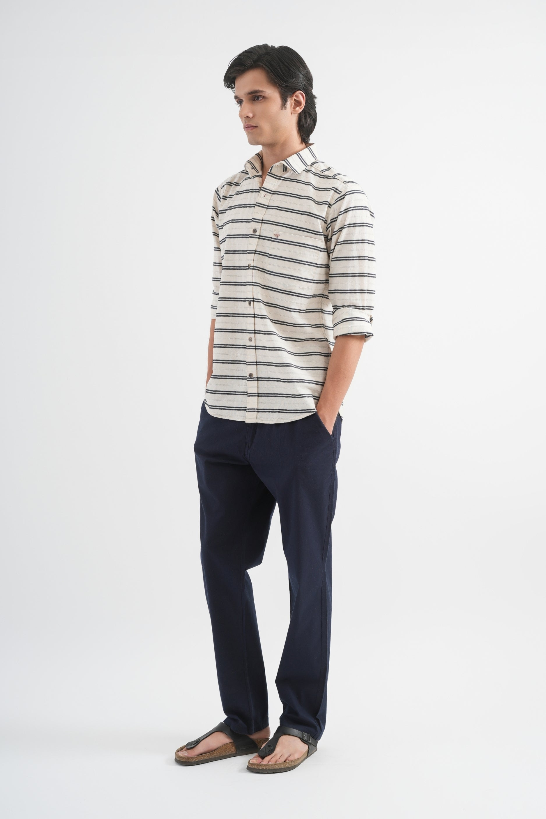 Man wearing a striped shirt and dark pants on a white background