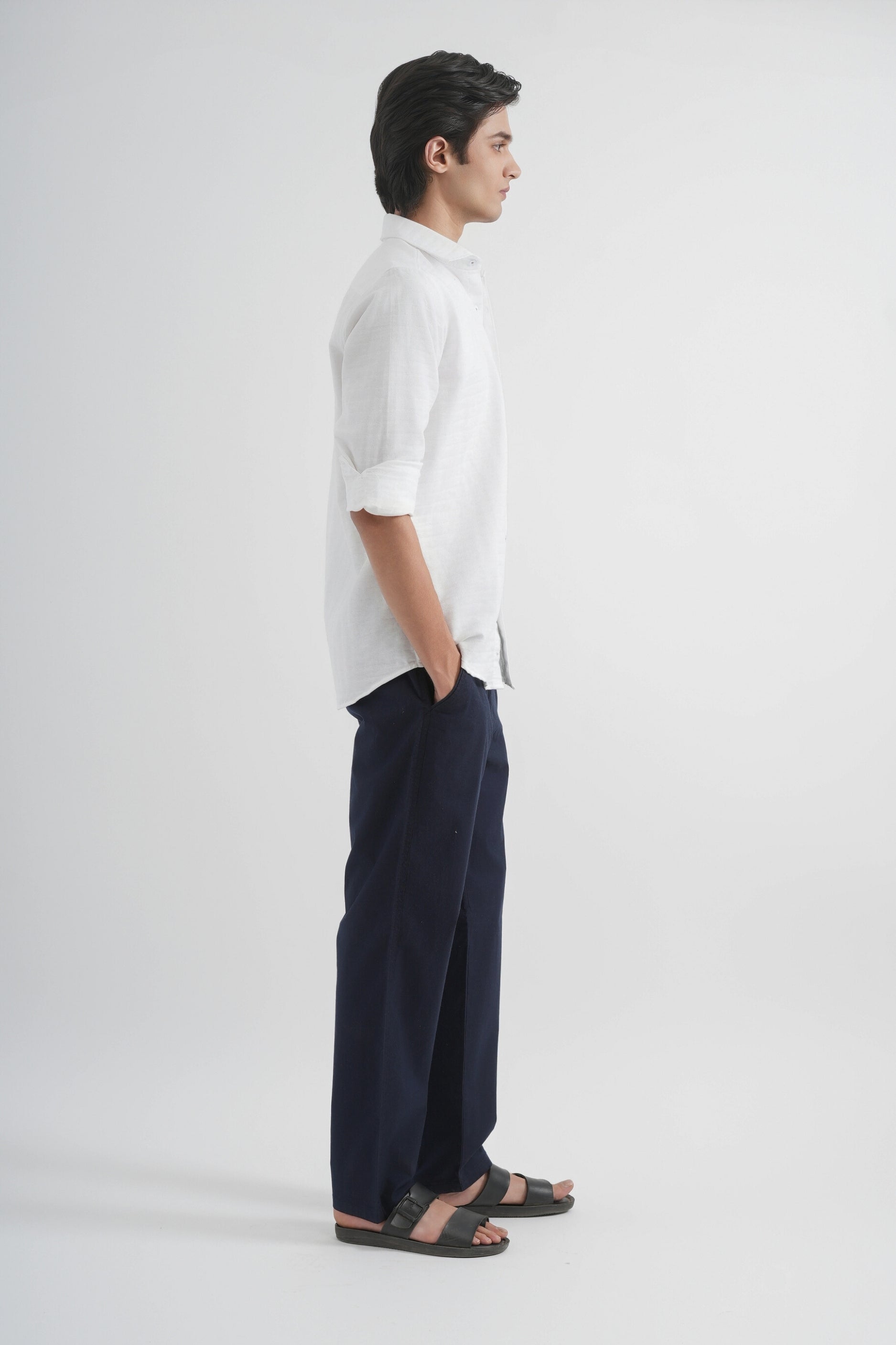 Man wearing a white shirt and dark pants on a white background