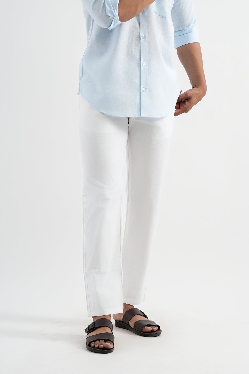 Person wearing a light blue shirt, white pants, and brown sandals on a white background