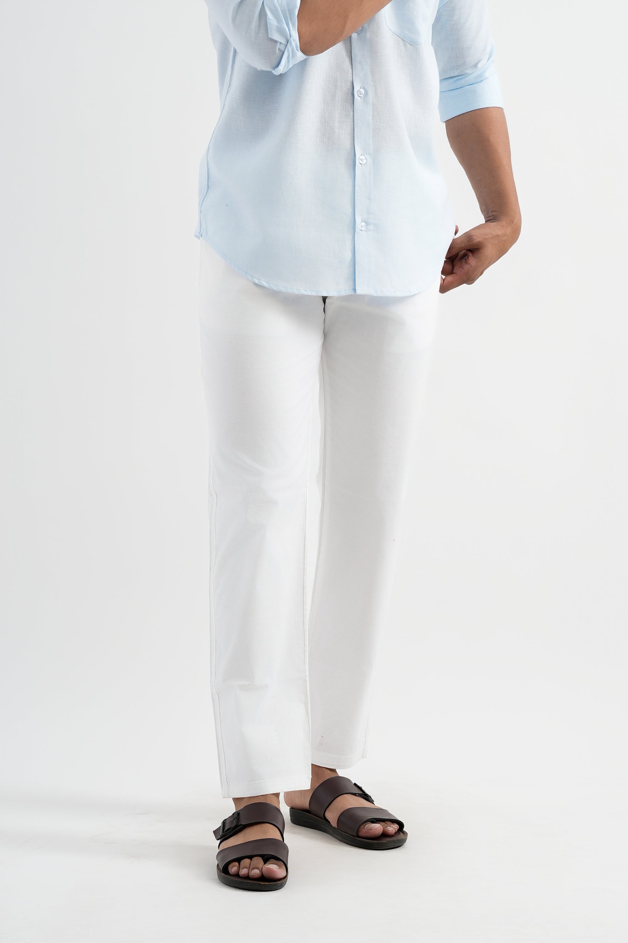 Person wearing a light blue shirt, white pants, and brown sandals on a white background