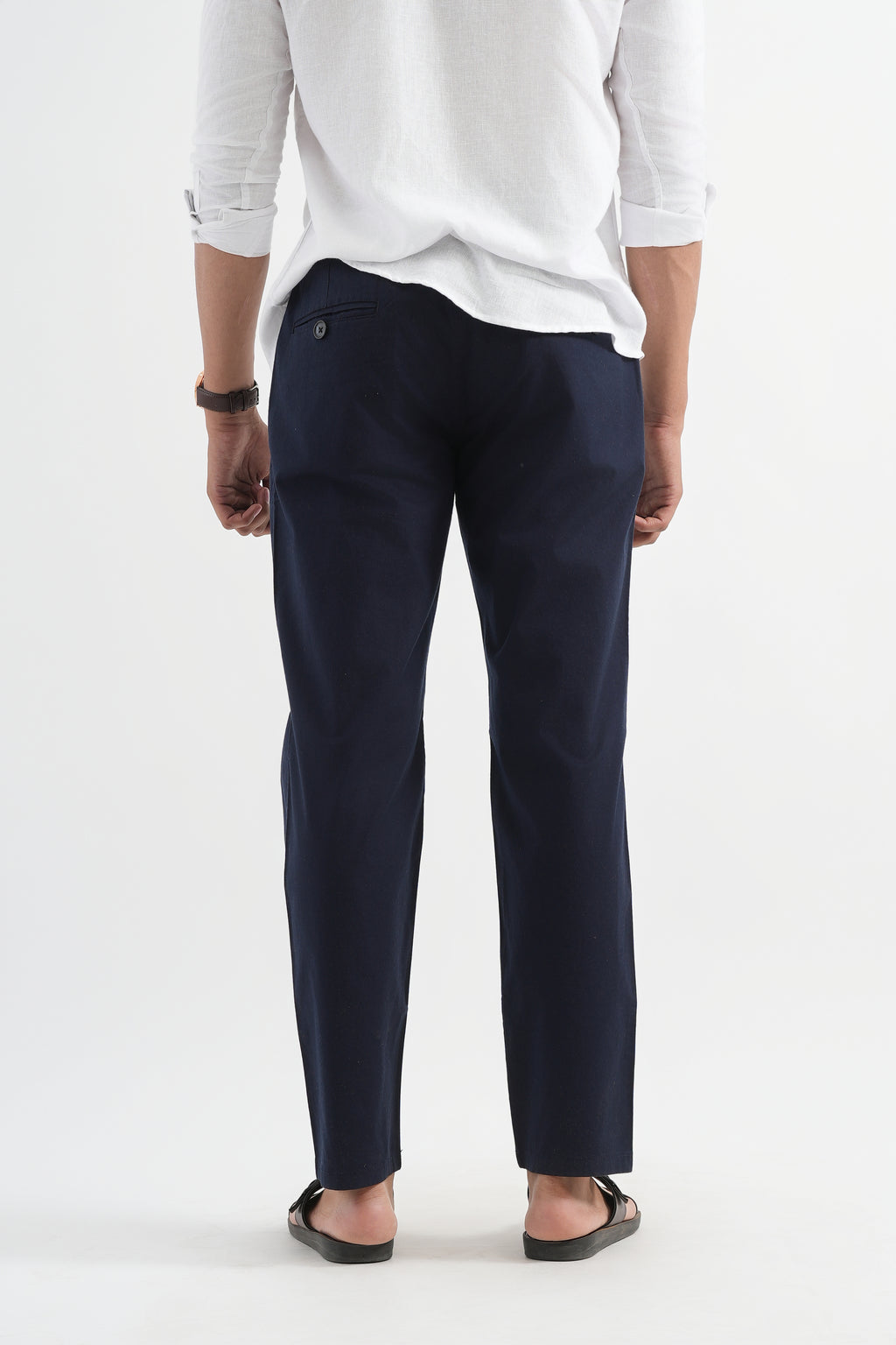 Person wearing navy pants and a white shirt on a white background