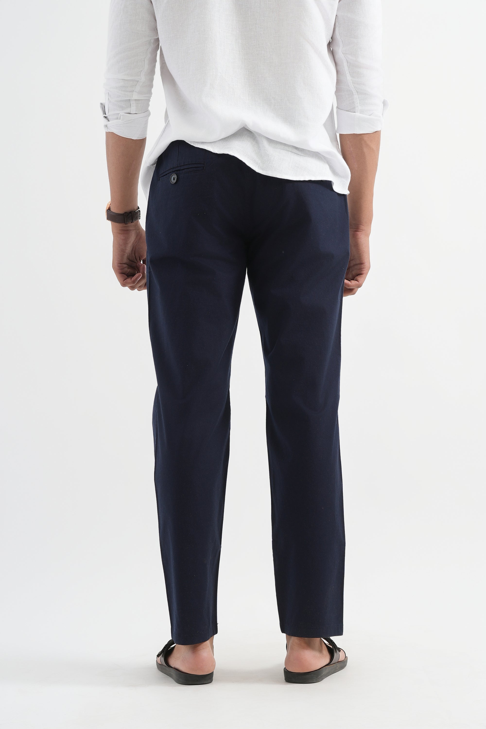 Person wearing navy pants and a white shirt on a white background