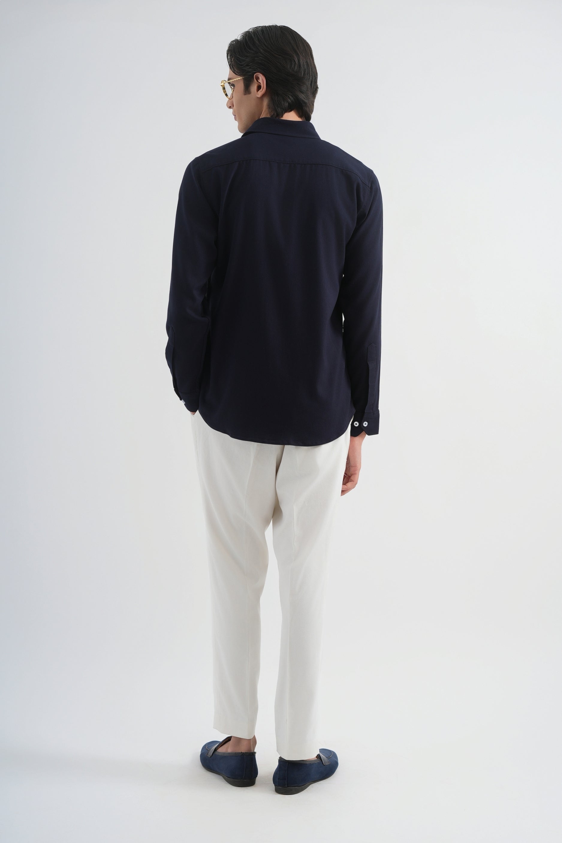 Man wearing a dark blue shirt and white pants on a white background