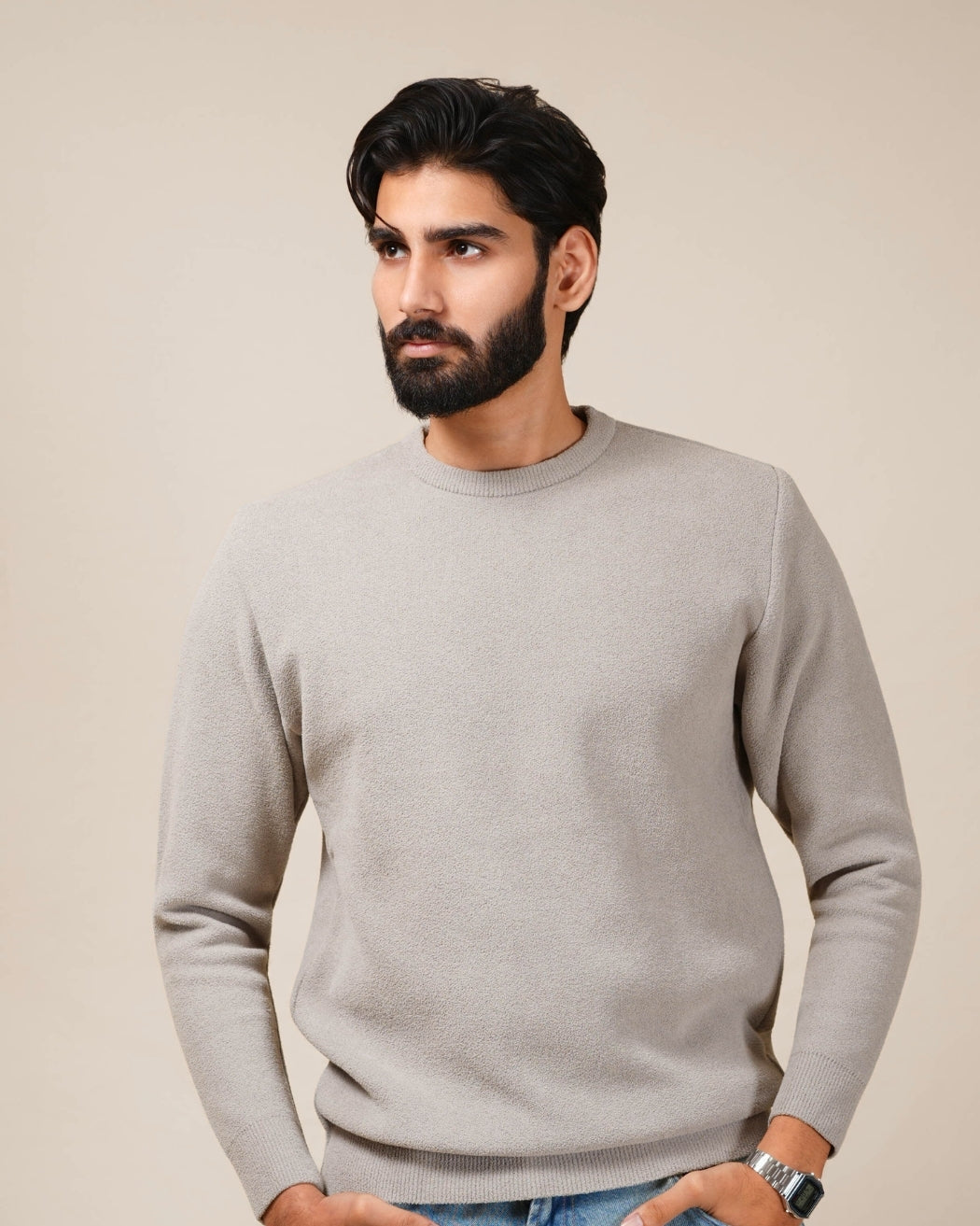 Man wearing a gray sweater against a beige background