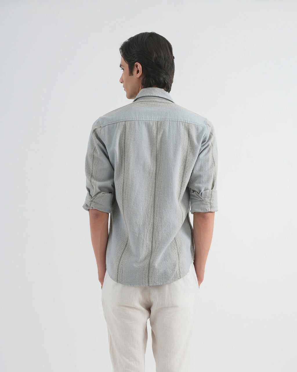 Person wearing a light gray shirt and white pants on a plain background