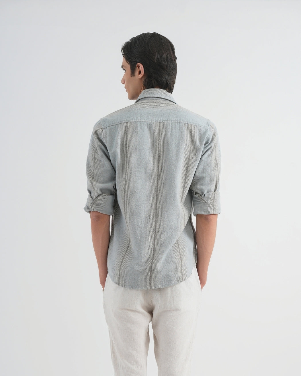 Person wearing a light gray shirt and white pants on a plain background
