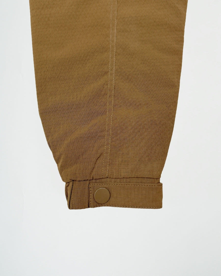 Close-up of brown corduroy pants with a button on a light gray background