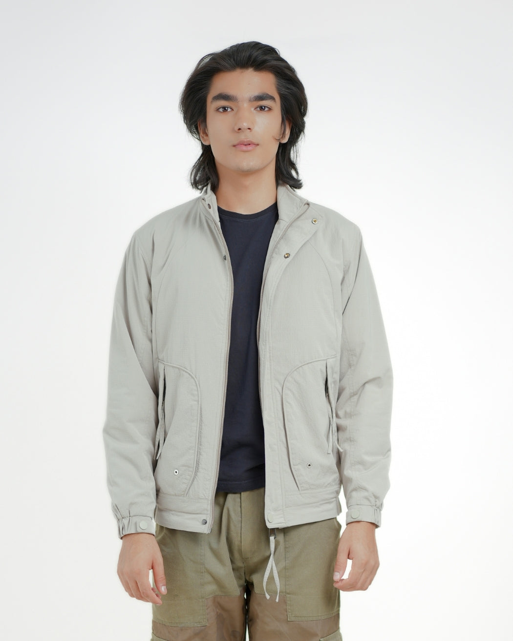 Person wearing a light gray jacket over a dark shirt with a white background