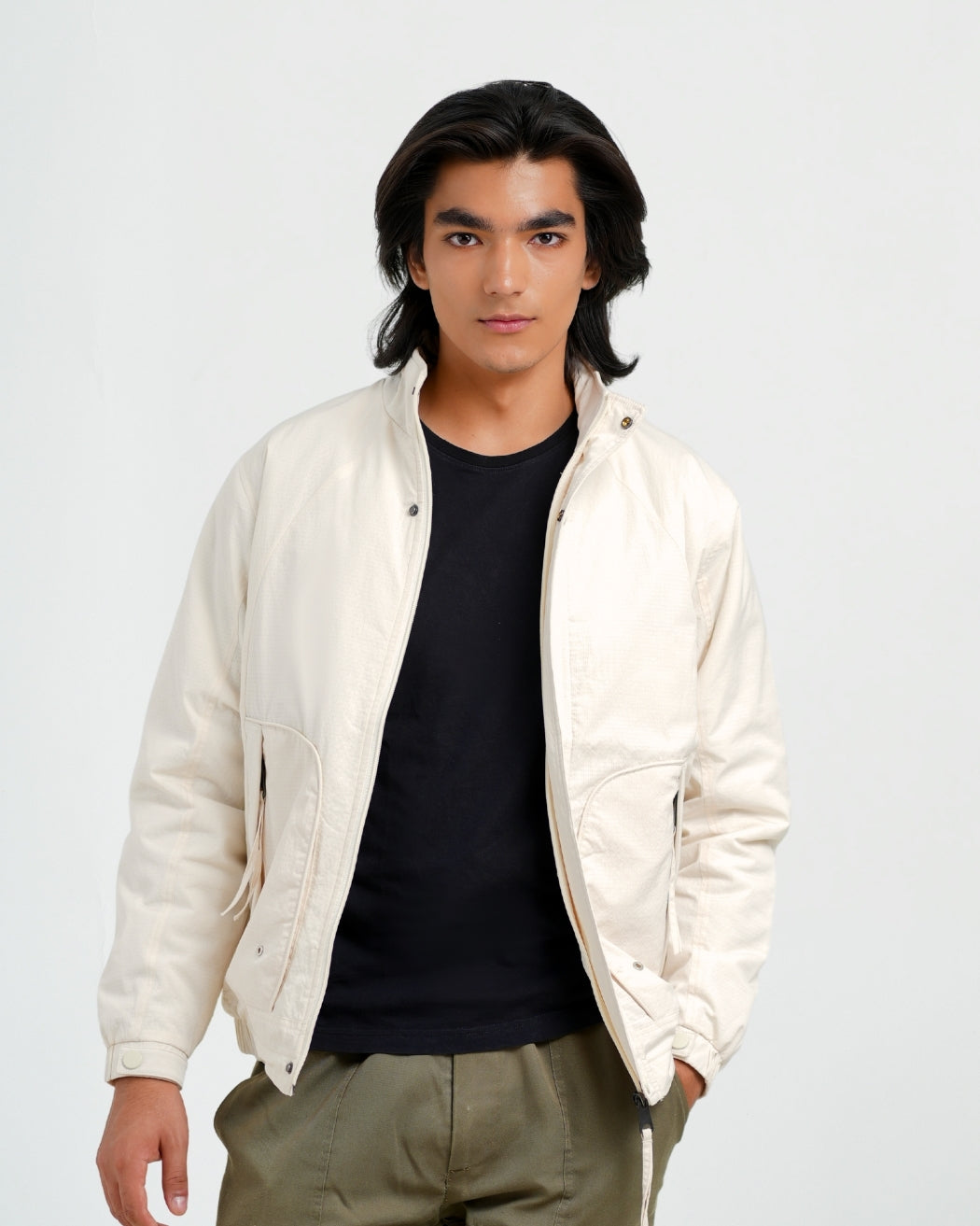 Man wearing a white jacket over a black shirt on a plain background