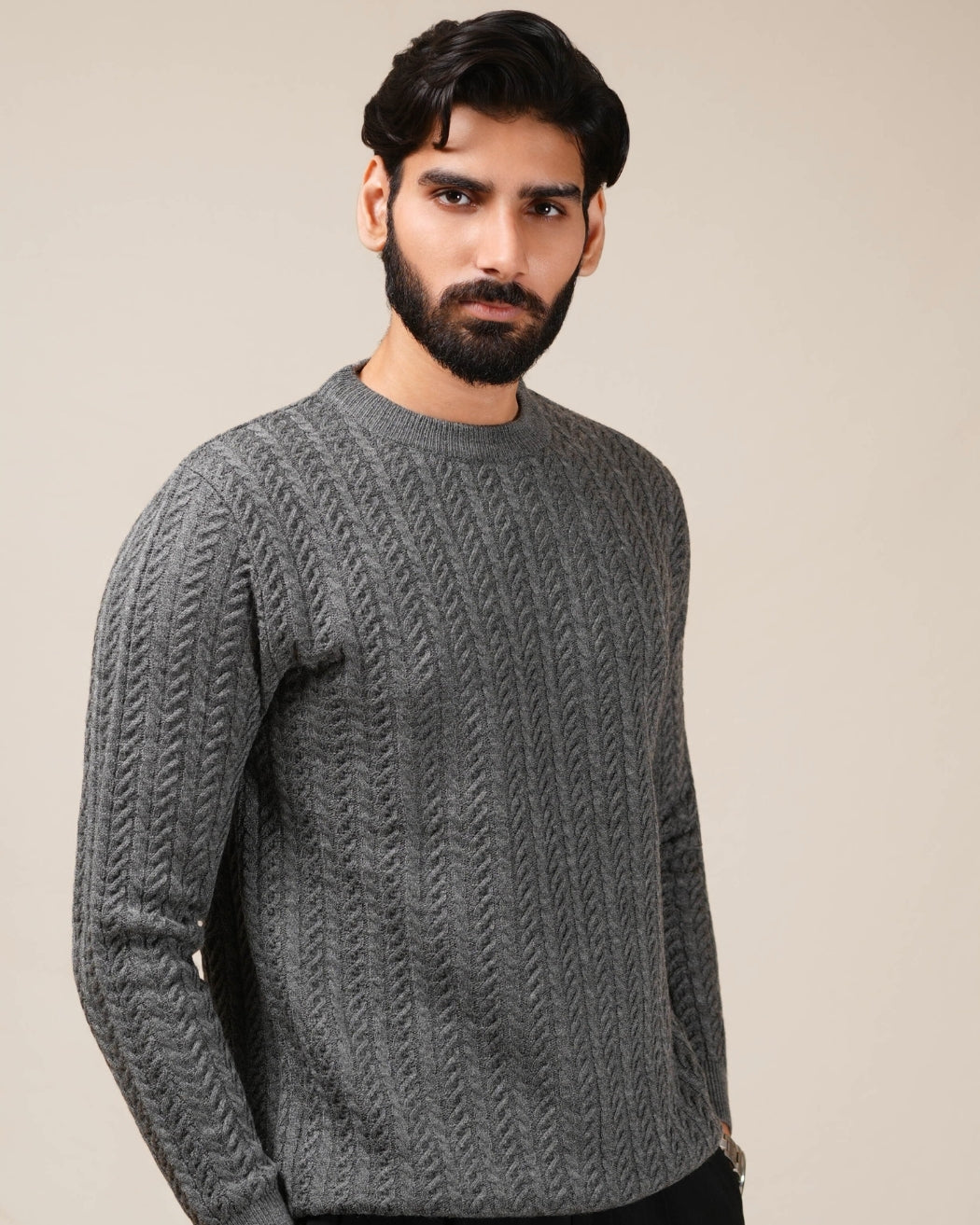 Man wearing a gray cable knit sweater against a beige background