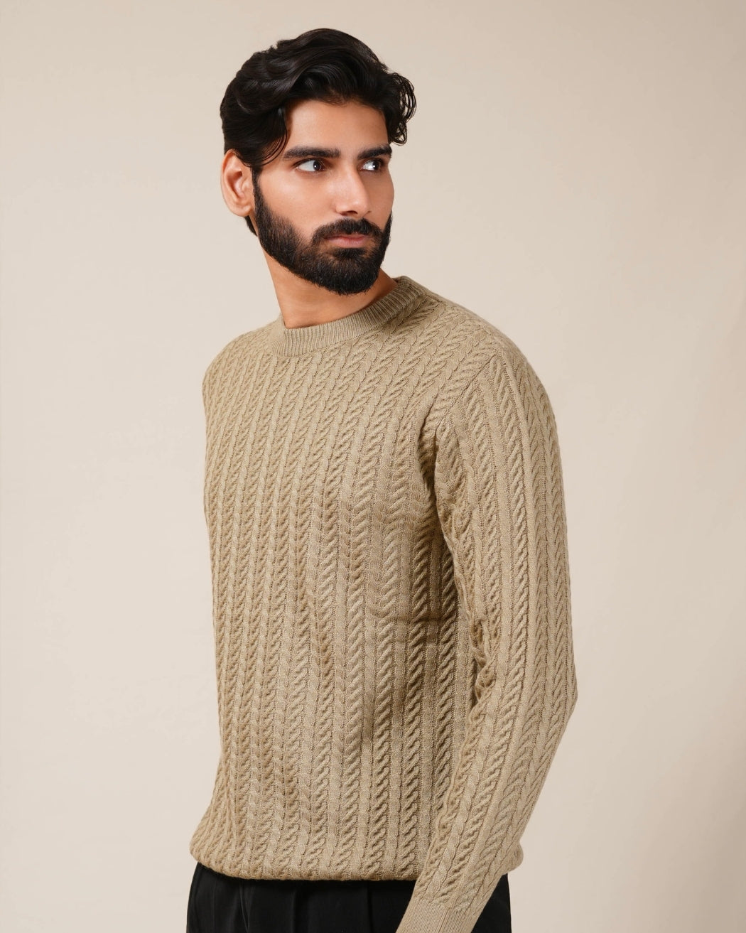 Man wearing a beige knitted sweater against a plain background