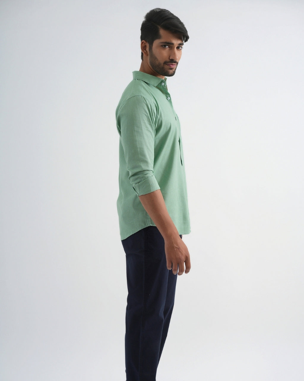 Man wearing a light green shirt and dark pants on a white background
