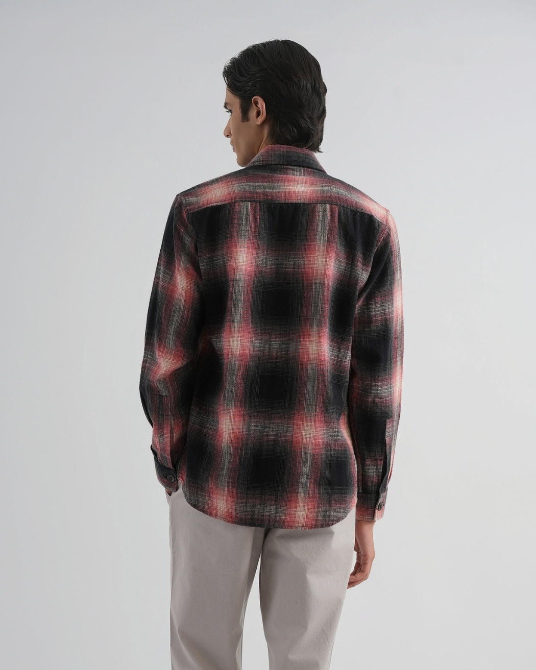 Person wearing a red and black plaid shirt on a white background
