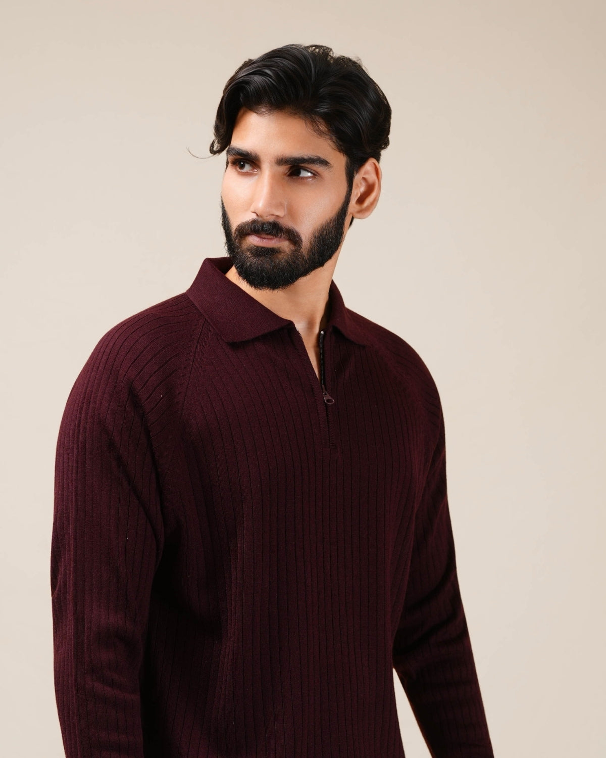 Man wearing a burgundy sweater against a beige background