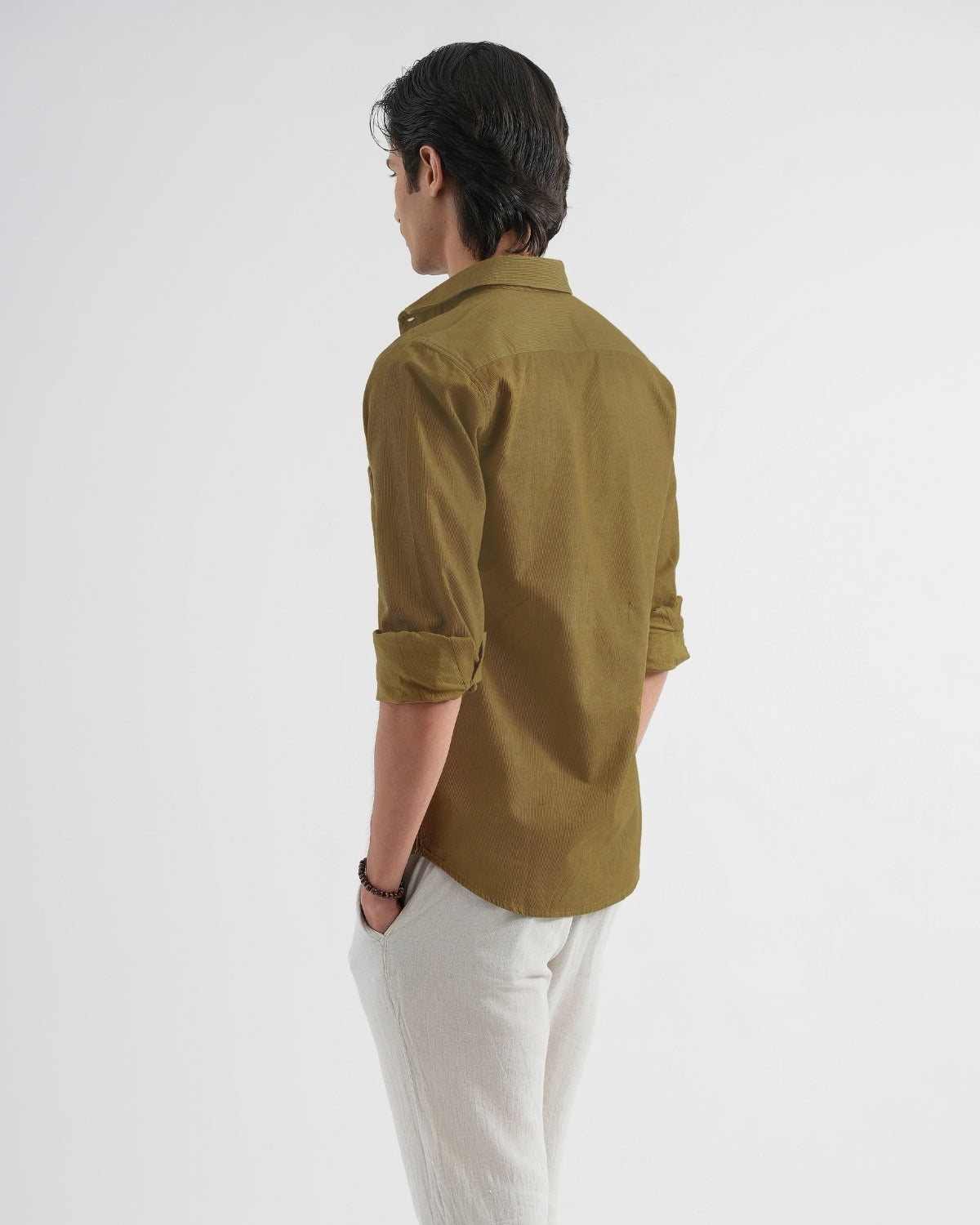 Person wearing a green shirt and white pants on a white background