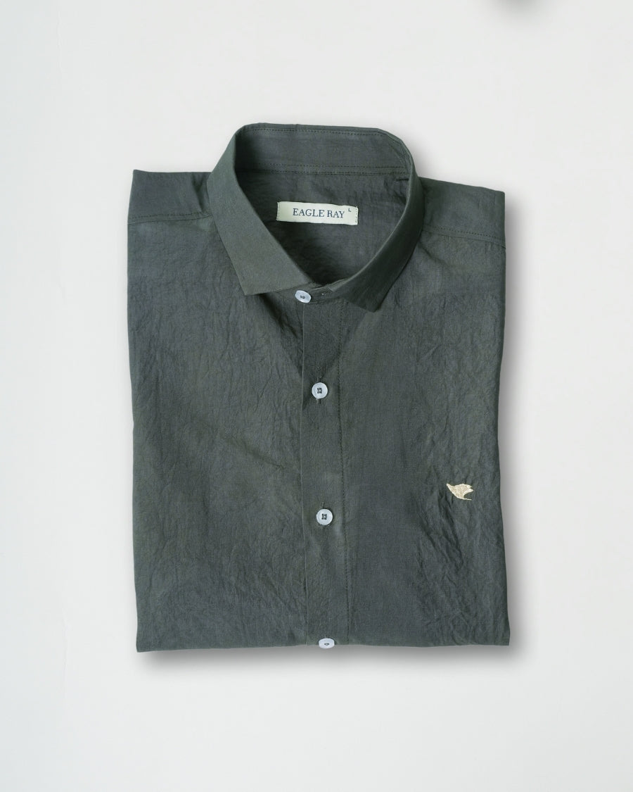 Folded dark green shirt with a brand label on a light gray background