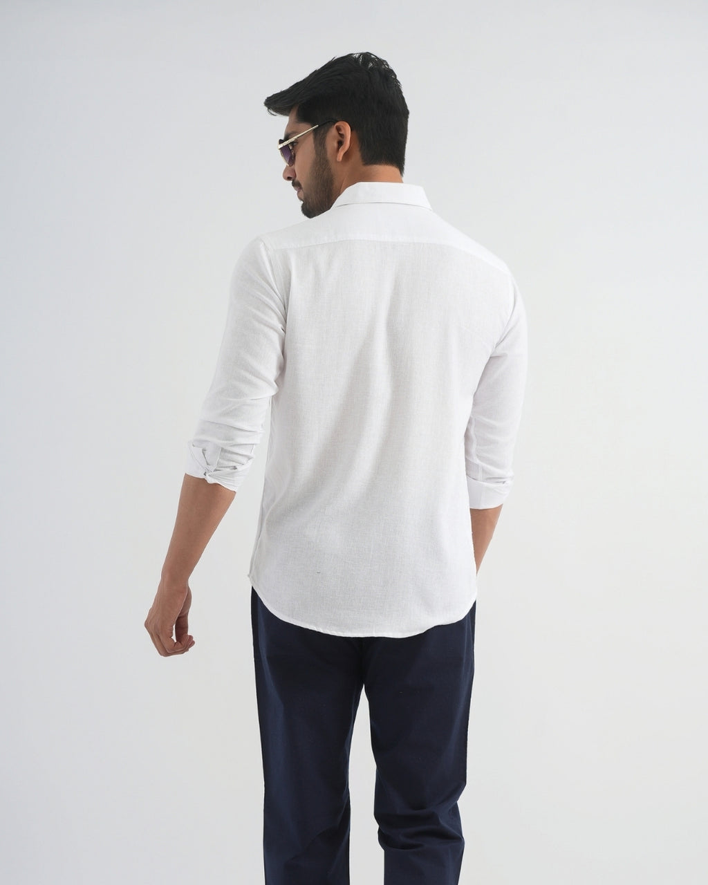Man wearing a white shirt and navy pants on a plain background