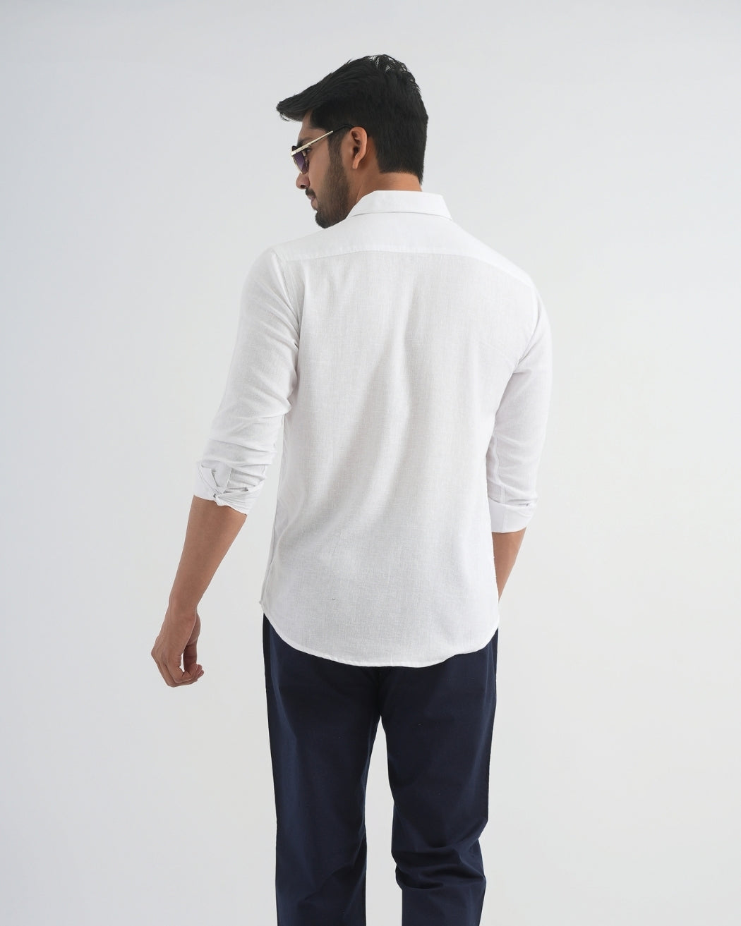 Man wearing a white shirt and navy pants on a plain background