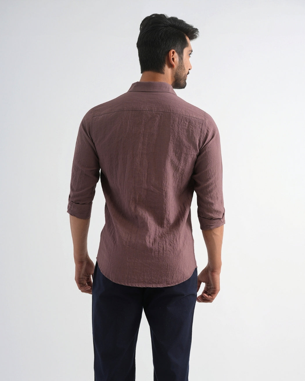 Man wearing a brown shirt and dark pants on a white background