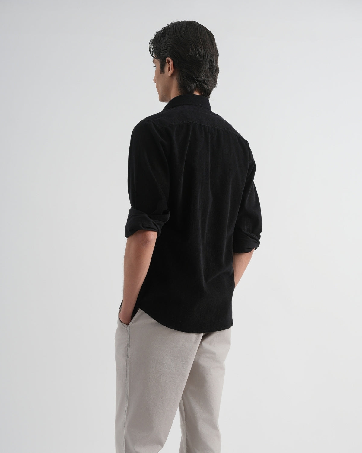 Person wearing a black shirt and light gray pants on a white background