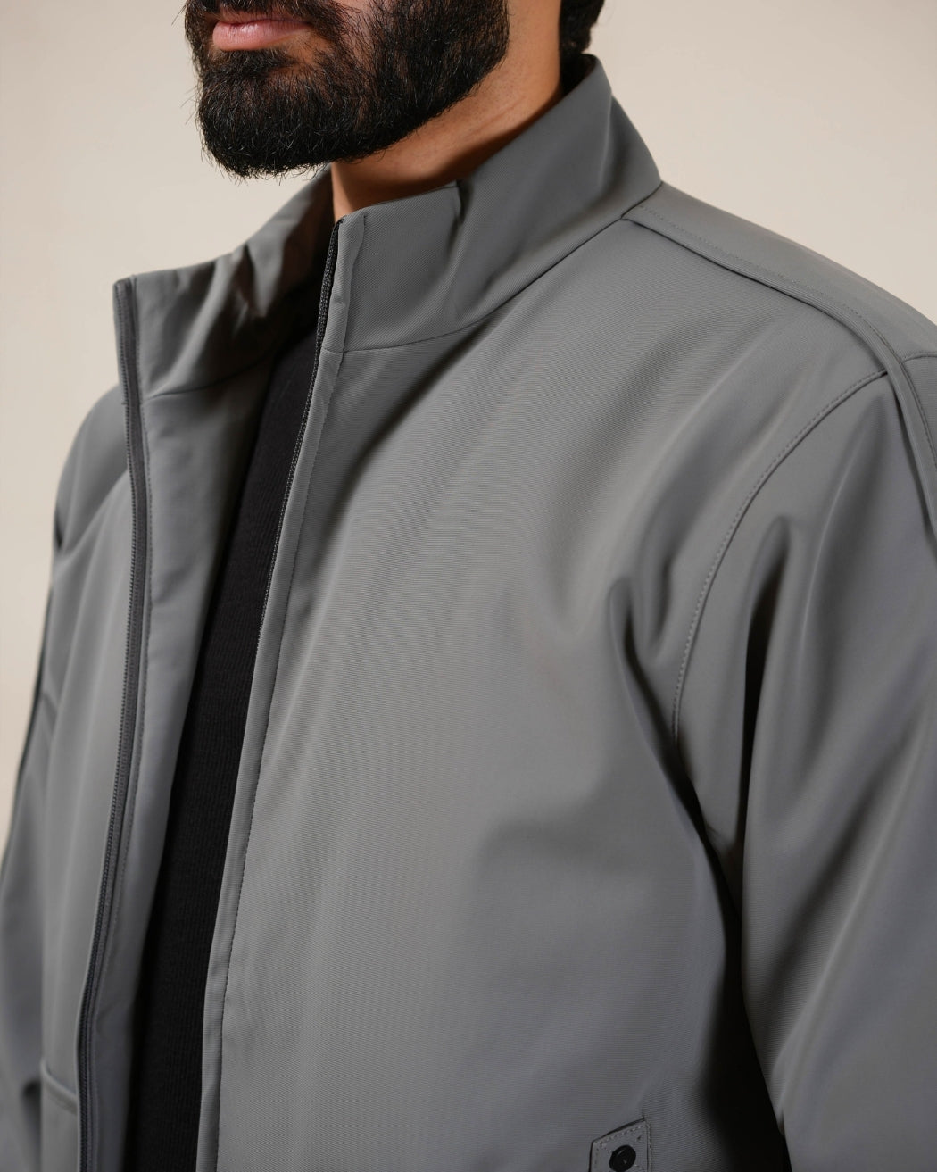 Person wearing a gray jacket with a neutral background