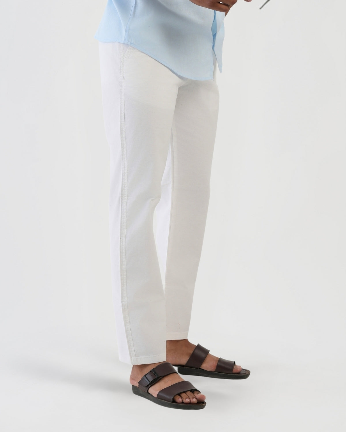 Person wearing white pants and brown sandals on a white background