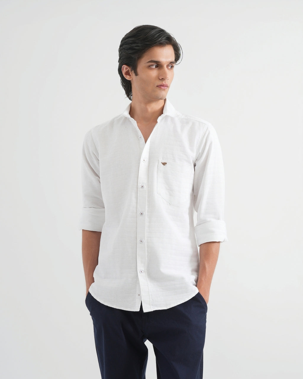 Man wearing a white shirt with rolled-up sleeves on a light gray background