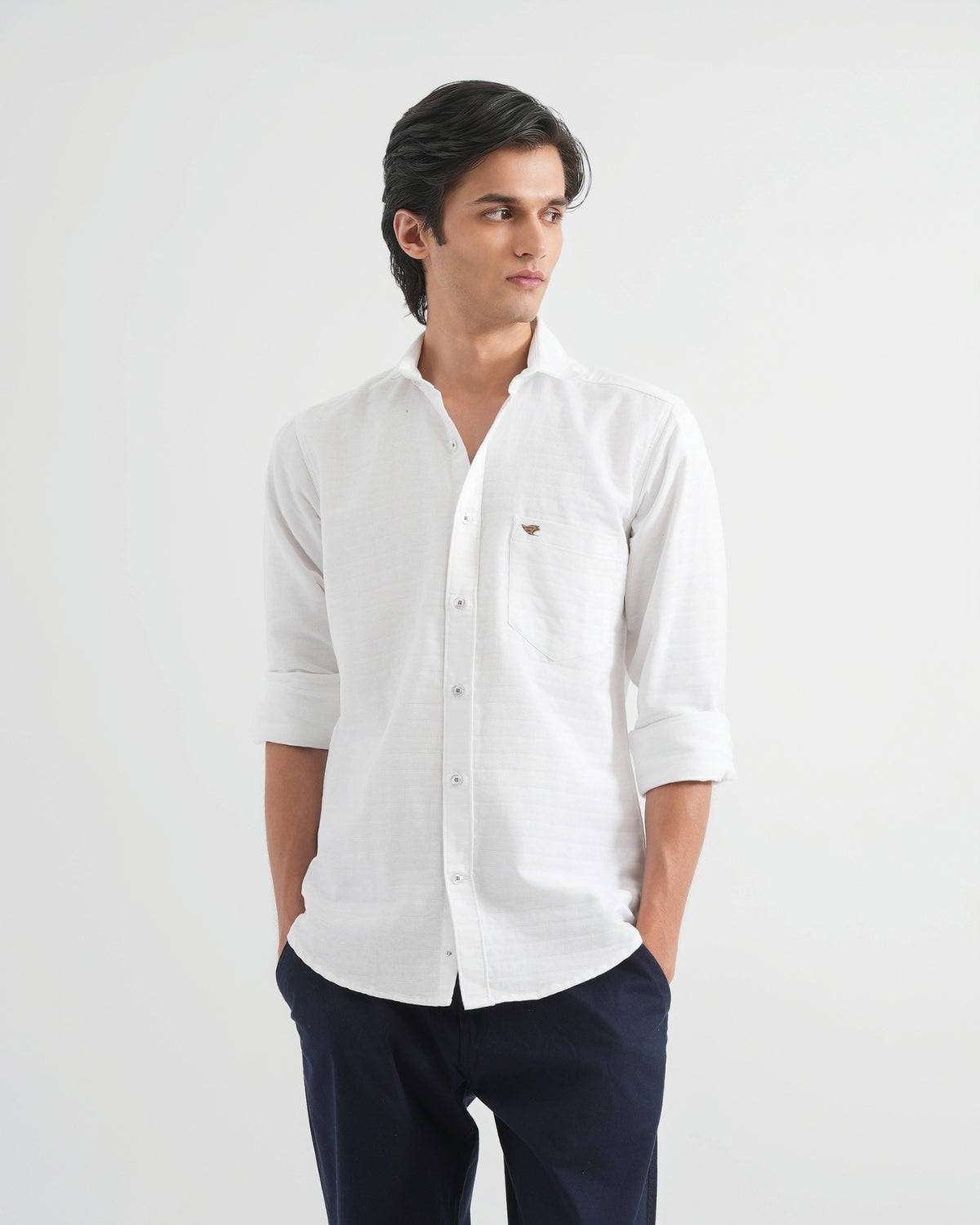 Man wearing a white shirt with rolled-up sleeves on a light gray background