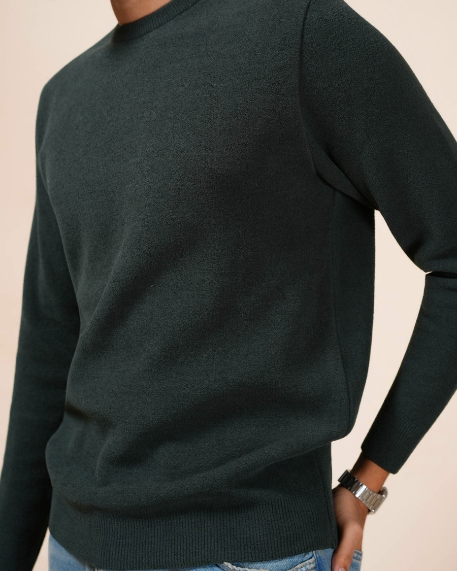 Dark green sweater worn by a person on a beige background