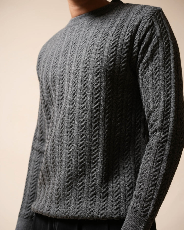 Close-up of a person wearing a textured gray sweater against a beige background