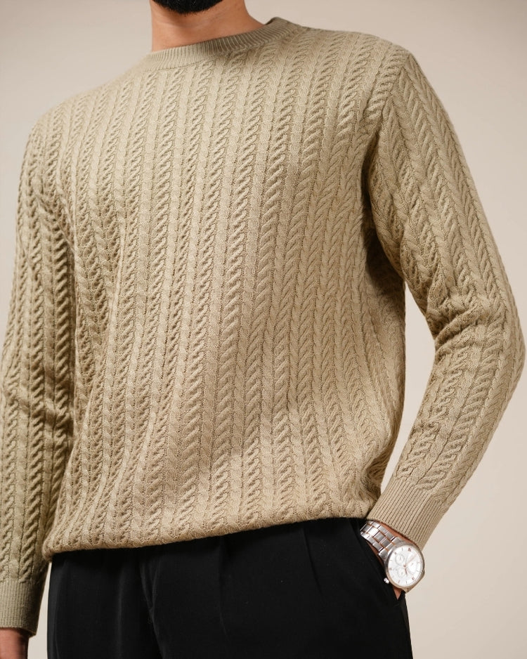 Beige cable knit sweater worn by a person on a plain background