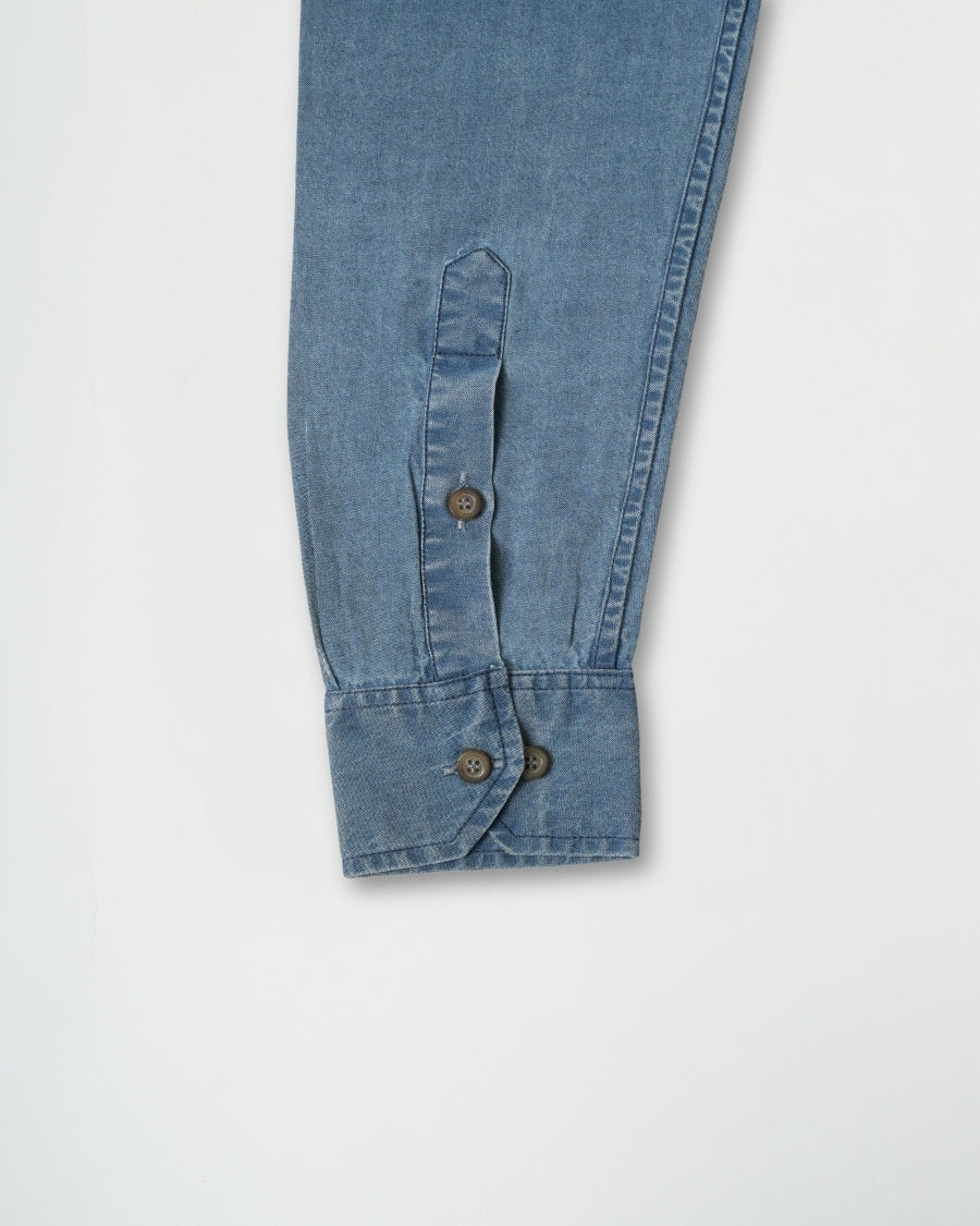 Close-up of blue denim pants with button details on a light gray background