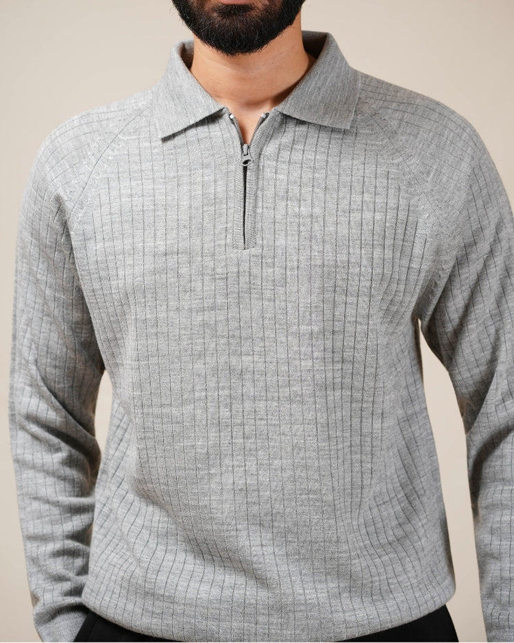 Person wearing a gray checkered sweater with a zipper on a plain background