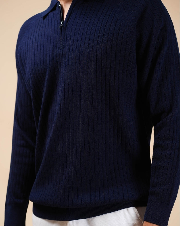 Navy blue ribbed sweater worn by a person on a beige background